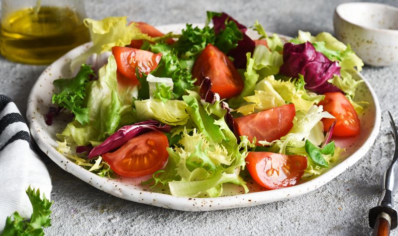 Ilustrasi salad Vegetable mix salad with tomatoes and sauce on a concrete background.