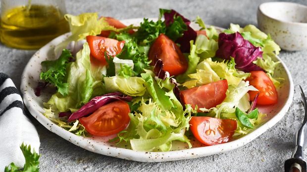 Ilustrasi salad Vegetable mix salad with tomatoes and sauce on a concrete background.
