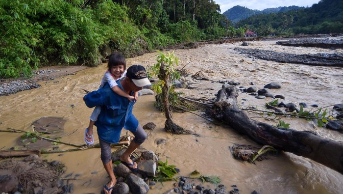 Sejumlah warga melewati tebing menggunakan tali di kawasan Batu Busuk, Pauh, Padang, Sumatera Barat, Selasa (16/12/2025). Akses jalan ke daerah terdampak banjir bandang itu kini terputus total karena banjir susulan pada Minggu (14/12/2025) merusak jalan darurat dan kini hanya bisa dilewati melalui tebing-tebing dan aliran sungai baru, sementara warga di sana terisolasi. ANTARA FOTO/Iggoy el Fitra