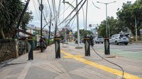 Kabel utilitas tampak semrawut dan menjuntai hingga ke trotoar di Jalan Prof Dr Soepomo, Tebet, Jakarta, Selasa (16/12/2025). Kondisi ini menutup jalur pejalan kaki.