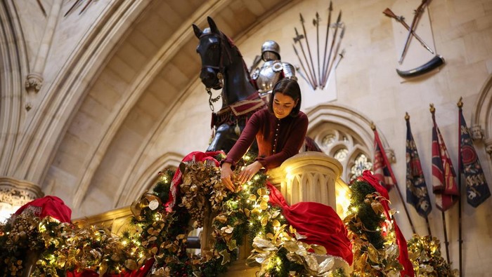 A staff member arranges garlands in the Grand Staircase in Windsor Castle during a media preview of the festive decorations at the royal residence, in Windsor, Britain, November 27, 2025. REUTERS/Isabel Infantes
