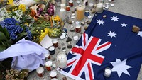 Karangan bunga, lilin menyala, serta sebuah bendera Australia terlihat tersusun rapi di tepi pantai sebagai bentuk solidaritas dan belasungkawa bagi para korban. REUTERS/Flavio Brancaleone