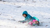 Seorang anak meluncur di salju. Aktivitas ini umum setelah salju setebal 5–10 cm, karena lapisan salju segar mengurangi gesekan dan terasa lebih aman untuk bermain. REUTERS/Eduardo Munoz
