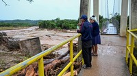 Dua warga mengamati luapan sungai di atas jembatan gantung di atas Sungai Pirai setelah banjir melanda kawasan tersebut. Jembatan ini menjadi jalur penting karena banyak jalan utama rusak atau tidak dapat dilalui akibat genangan air.REUTERS/Claudia Morales