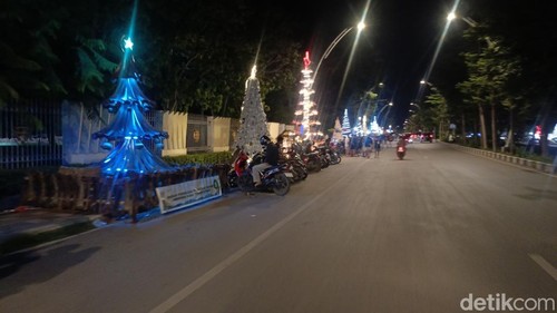 Deretan pohon Natal dengan kerlap-kerlip lampu saat malam hari menghiasi ruas Jalan El Tari Kupang, NTT, Rabu (17/12/2025). (Foto: Simon Selly/detikBali)