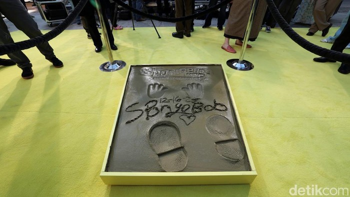 People stand next to prints in cement left by SpongeBob SquarePants during a ceremony to celebrate the release of the film 
