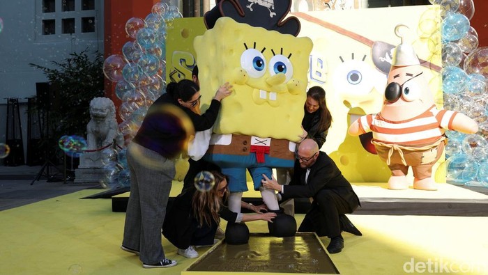 People stand next to prints in cement left by SpongeBob SquarePants during a ceremony to celebrate the release of the film 