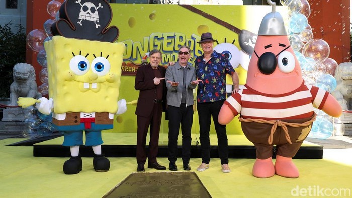 People stand next to prints in cement left by SpongeBob SquarePants during a ceremony to celebrate the release of the film 