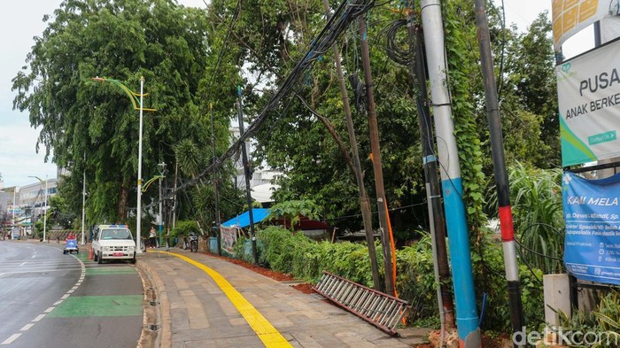 Petugas Suku Dinas Bina Marga Jakarta Selatan menata kabel utilitas yang sebelumnya menjuntai rendah di trotoar Jalan Soepomo, Tebet, Rabu (17/12/2025).