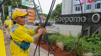 Petugas Suku Dinas Bina Marga Jakarta Selatan menata kabel utilitas yang sebelumnya menjuntai rendah di trotoar Jalan Soepomo, Tebet, Rabu (17/12/2025).