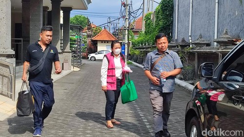 Putu Rina mantan Mantri BRI unit Ngurah Rai, Kelurahan Loloan Barat, Jembrana berjalan menuju mobil dikawal petugas Kejari Jembrana, Rabu (17/12/2025). (Ahmad Firizqi Irwan/detikBali).