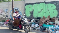 Seorang pengendara motor sedang melintas disamping tumpukan sampah di Jalan Kalibokor, Gubeng, Surabaya.