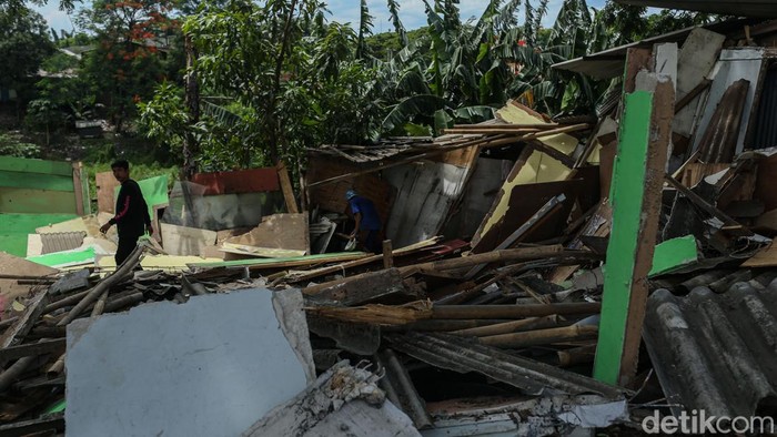 Warga beraktivitas di samping runtuhan bangunan liar di sepanjang bantaran Kalimalang, Cikarang, Kabupaten Bekasi, Rabu (17/12/2025).