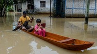 Seorang bapak bersama anaknya menggunakan perahu kayu menerobos banjir di Kampung Kajaroan, Cinangka, Kabupaten Serang, Banten, Kamis (18/12/2025). ANTARA FOTO/Muhammad Bagus Khoirunas