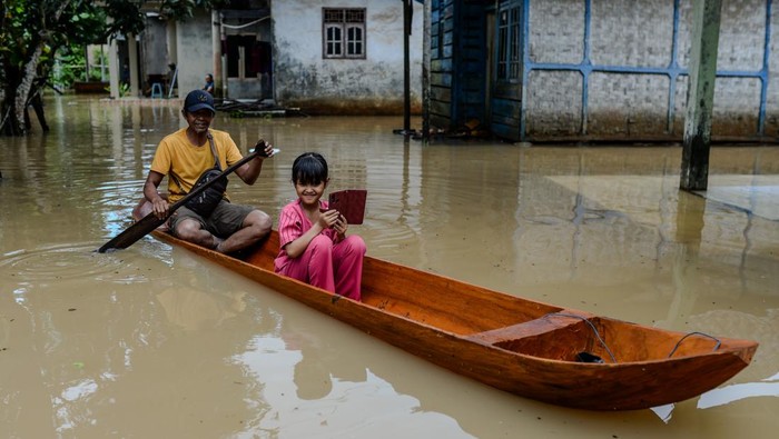 Seorang bapak bersama anaknya menggunakan perahu kayu menerobos banjir di Kampung Kajaroan, Cinangka, Kabupaten Serang, Banten, Kamis (18/12/2025). BPBD Kabupaten Serang mencatat hingga Kamis (18/12) sebanyak 2.125 jiwa di tiga kecamatan di Kabupaten Serang terdampak bencana banjir akibat curah hujan tinggi yang terjadi sejak empat hari terakhir dengan ketinggian banjir berkisar 50-80 cm. ANTARA FOTO/Muhammad Bagus Khoirunas