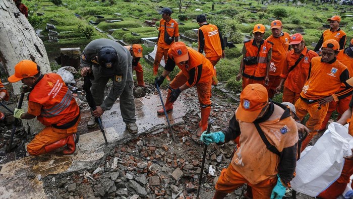 Petugas membawa barang bongkaran lapak usaha di TPU Kober Rawa Bunga, Jatinegara, Jakarta, Kamis (18/12/2025). Pemprov DKI Jakarta akan mengembalikan fungsi lahan di TPU Kober Rawa Bunga yang sebelumnya digunakan sebagai tempat usaha menjadi pemakaman yang dapat menampung 450 petak makam. ANTARA FOTO/Asprilla Dwi Adha