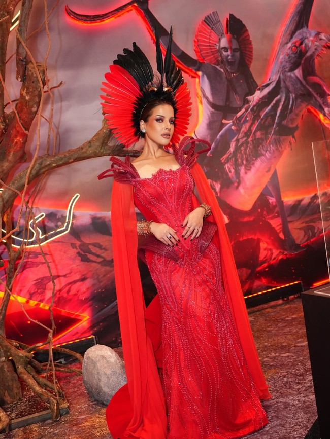 Latar instalasi bertema Pandora, karakter Na’vi, serta pencahayaan bernuansa merah-oranye semakin memperkuat kesan dramatis dari keseluruhan tampilannya. Gaun merah menyala rancangan khusus Andreas Odang menjadi pusat perhatian. (Foto: Instagram/@tasyafarasya)