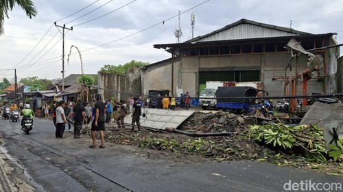 Warga membersihkan reruntuhan tembok yang roboh di Jalan Kebo Iwa Utara, Banjar Batukandik, Padangsambian Kaja, Denpasar Barat. Kamis (18/12/2025).