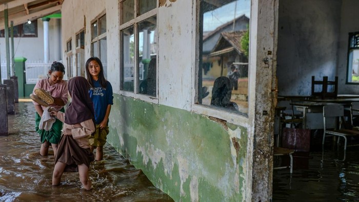 Sejumlah anak berjalan menerobos banjir di Kampung Sukamaju, Padarincang, Kabupaten Serang, Banten, Jumat (19/12/2025). BPBD Kabupaten Serang mencatat hingga Jumat (19/12) daerah terdampak banjir meluas di enam kecamatan dari hari sebelumnya hanya tiga kecamatan, dengan ketinggian air 50cm hingga mencapai satu meter. ANTARA FOTO/Muhammad Bagus Khoirunas