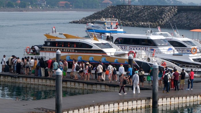 Wisatawan berjalan di dermaga apung saat akan menyeberang ke Pulau Nusa Penida menggunakan kapal cepat di Pelabuhan Sanur, Denpasar, Bali, Jumat (19/12/2025). Kantor Kesyahbandaran dan Otoritas Pelabuhan (KSOP) Kelas II Benoa, Bali, memastikan kelaikan 67 kapal cepat atau boat di Pelabuhan Sanur dan Serangan Denpasar untuk melayani peningkatan penumpang pariwisata jelang libur Natal dan Tahun Baru 2026. ANTARA FOTO/Nyoman Hendra Wibowo