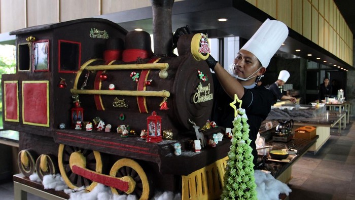 Koki patiseri Kurniawan Yusuf Indra Bagus membenahi posisi pernik miniatur kereta Natal berbahan cokelat di Hotel Grand Mercure, Malang, Jumat (19/12/2025). Miniatur kereta Natal dari cokelat setinggi satu meter dengan bobot 65 kilogram tersebut dibuat selama satu minggu untuk memeriahkan suasana Natal sekaligus menyampaikan semangat keberagaman dan perjalanan menuju kegembiraan melalui simbol kereta api. ANTARA FOTO/Ari Bowo Sucipto