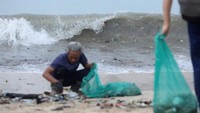 Relawan membersihkan sampah yang bercampur dengan ombak di bibir Pantai Kedonganan agar kebersihan lingkungan dan aktivitas warga kembali pulih. REUTERS/Johannes P. Christo