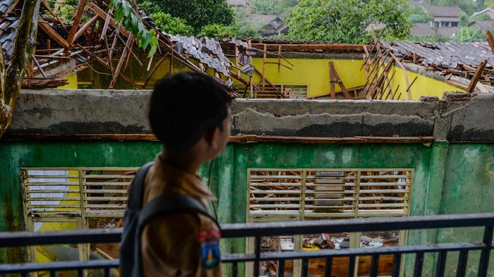 Siswa mengamati kondisi atap ruang perpustakaan yang ambruk di SMP Negeri Satap Cibulakan, Kabupaten Serang, Banten, Jumat (19/12/2025). Menurut pihak sekolah, ruang perpustakaan tersebut ambruk pada Kamis (18/12) dini hari karena faktor bangunan yang sudah lama dan lapuk serta imbas hujan lebat disertai angin kencang yang terjadi sejak beberapa hari terakhir. ANTARA FOTO/Muhammad Bagus Khoirunas