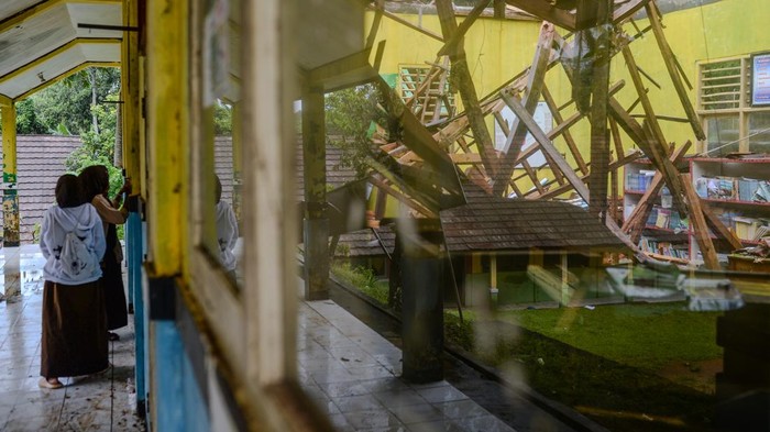 Siswa mengamati kondisi atap ruang perpustakaan yang ambruk di SMP Negeri Satap Cibulakan, Kabupaten Serang, Banten, Jumat (19/12/2025). Menurut pihak sekolah, ruang perpustakaan tersebut ambruk pada Kamis (18/12) dini hari karena faktor bangunan yang sudah lama dan lapuk serta imbas hujan lebat disertai angin kencang yang terjadi sejak beberapa hari terakhir. ANTARA FOTO/Muhammad Bagus Khoirunas