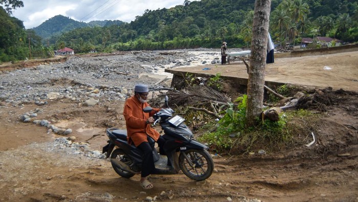 Petugas mendorong mobil ambulan saat melewati jalan darurat di Batu Busuk, Padang, Sumatera Barat, Jumat (19/12/2025). Jalan darurat tersebut kembali dibuka untuk sepeda motor dan mobil setelah beberapa waktu lalu diterjang banjir susulan sehingga membuat akses ke lokasi terdampak banjir bandang itu putus dan sempat terisolasi. ANTARA FOTO/Iggoy el Fitra/nym.
