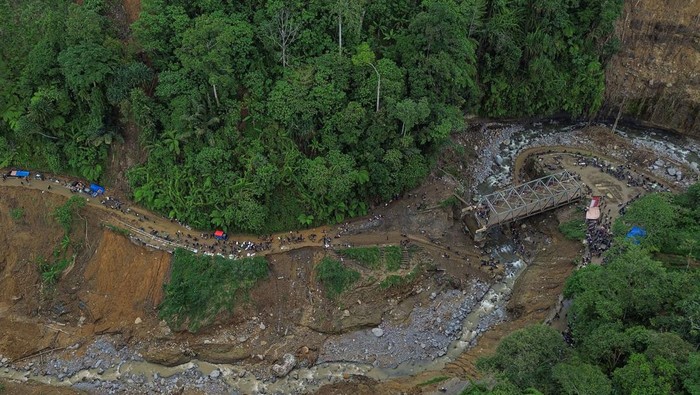 Warga mengangkat sepeda motor saat menyeberangi sungai wilayah Tenge Besi, Kecamatan Pintu Rime Gayo, Kabupaten Bener Meriah, Aceh, Sabtu (20/12/2025). Akses warga pejalan kaki masih harus melintasi jembatan darurat dari batang kayu dan kendaraan roda dua harus menyeberangi arus sungai saat debit air surut, sementara roda empat tidak dapat melintas, akibat jalan dan jembatan penghubung antara Bener Meriah menuju Takengon, Kabupaten Aceh Tengah putus diterjang banjir bandang pada Rabu (26/11). ANTARA FOTO/Khalis Surry/foc.