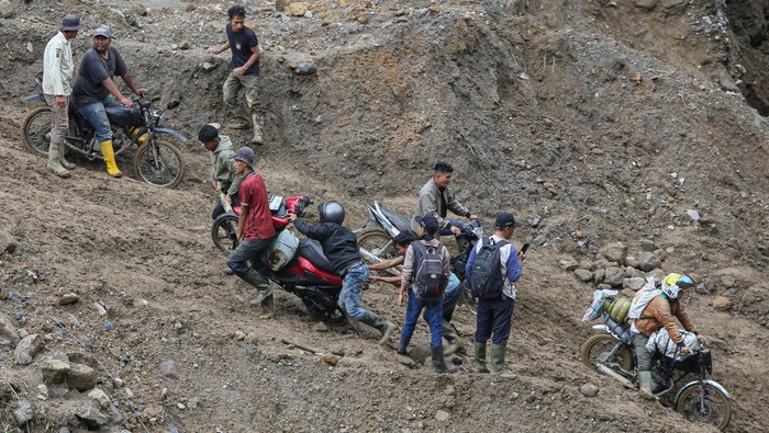 Warga mengangkat sepeda motor saat menyeberangi sungai wilayah Tenge Besi, Kecamatan Pintu Rime Gayo, Kabupaten Bener Meriah, Aceh, Sabtu (20/12/2025). Akses warga pejalan kaki masih harus melintasi jembatan darurat dari batang kayu dan kendaraan roda dua harus menyeberangi arus sungai saat debit air surut, sementara roda empat tidak dapat melintas, akibat jalan dan jembatan penghubung antara Bener Meriah menuju Takengon, Kabupaten Aceh Tengah putus diterjang banjir bandang pada Rabu (26/11). ANTARA FOTO/Khalis Surry/foc.