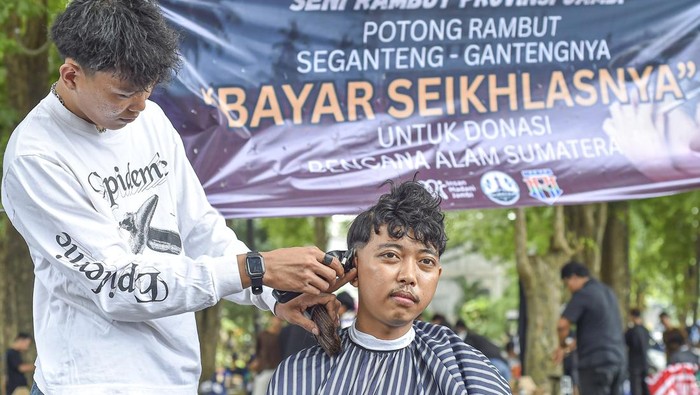 Kapster dari Seni Rambut Provinsi Jambi memangkas rambut warga saat penggalangan dana melalui aksi pangkas rambut bayar seikhlasnya di Taman Banjuran Budayo, Kota Baru, Jambi, Minggu (21/12/2025). Aksi yang diikuti 70 kapster se-Provinsi Jambi itu bertujuan menggalang dana untuk didonasikan ke warga korban bencana alam di Aceh, Sumatera Utara, dan Sumatera Barat. ANTARA FOTO/Wahdi Septiawan/bar
