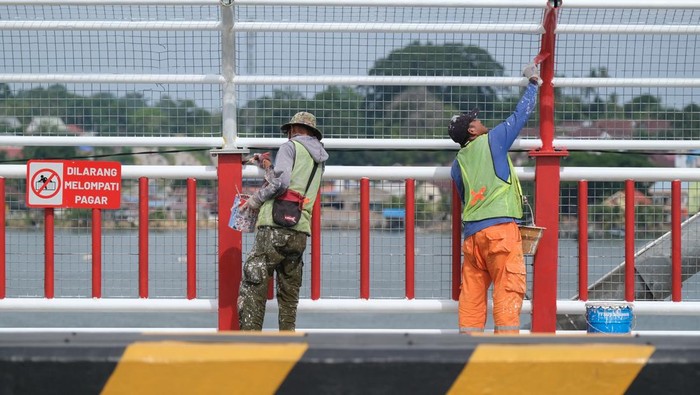 Sejumlah pekerja menyelesaikan pengecatan pagar pengaman Jembatan Teluk Kendari, Kendari, Sulawesi Tenggara, Minggu (21/12/2025). Balai Pelaksanaan Jalan Nasional (BPJN) memasang pagar pengaman setinggi 2,5 meter sepanjang 477 meter pada jembatan tersebut guna menghindari insiden terjun yang menelan tiga korban jiwa selama tahun 2025. ANTARA FOTO/Andry Denisah/bar