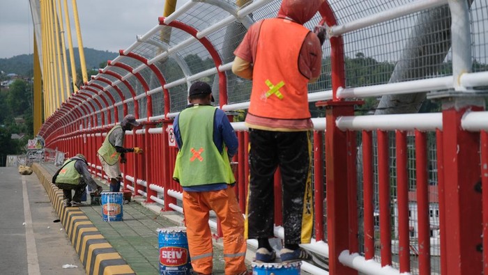 Sejumlah pekerja menyelesaikan pengecatan pagar pengaman Jembatan Teluk Kendari, Kendari, Sulawesi Tenggara, Minggu (21/12/2025). Balai Pelaksanaan Jalan Nasional (BPJN) memasang pagar pengaman setinggi 2,5 meter sepanjang 477 meter pada jembatan tersebut guna menghindari insiden terjun yang menelan tiga korban jiwa selama tahun 2025. ANTARA FOTO/Andry Denisah/bar