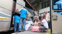 Sejumlah kru bus membantu penumpang menaikan bagasi ke dalam bus.