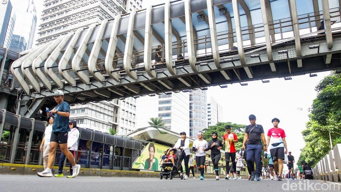 Warga berjalan kaki menikmati suasana Hari Bebas Kendaraan Bermotor (HBKB) di kawasan Sudirman, Jakarta, Minggu (21/12/2025).
