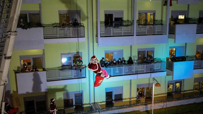 A Greek firefighter, dressed as Santa Claus, hands over a Christmas gift to a young patient of the 