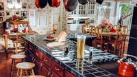 Dapur dan ruang makan di rumah ini juga sangat ikonik. Terdapat kitchen island atau meja atau kabinet dapur tambahan yang berdiri sendiri di tengah ruangan. Dinding ruangan masih didominasi dengan wallpaper bermotif yang memang membuat rumah ini terasa sangat khas. Terdapat kursi dan meja makan di samping kabinet yang bentuknya juga mendukung nuansa vintage di ruang makan.  Foto: @chicago.r3altor via Instagram