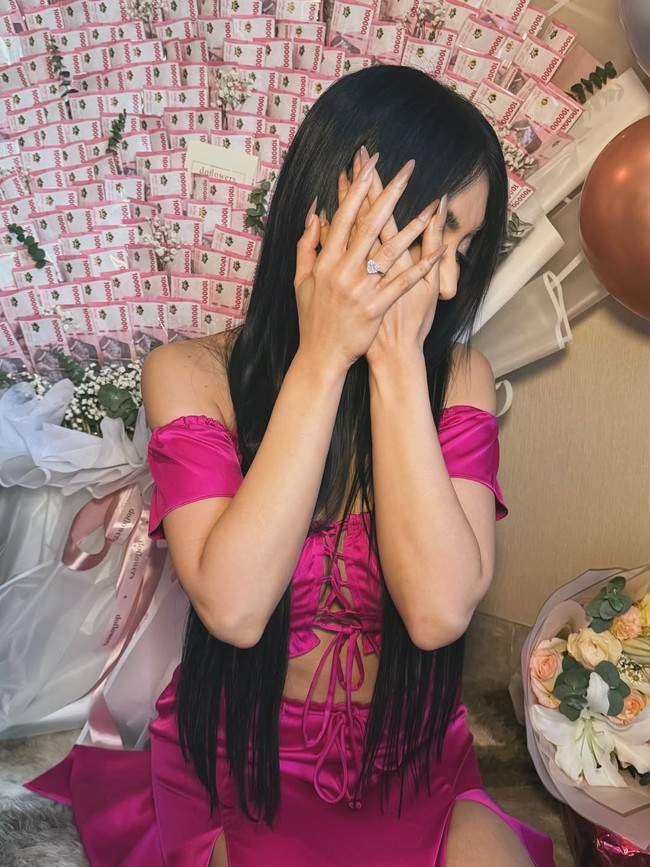 Selain buket uang, Denada juga menerima buket bunga putih elegan yang didominasi bunga lili. Dalam salah satu foto close-up, terlihat tangan Denada menyentuh rangkaian bunga tersebut sambil memperlihatkan sebuah cincin berlian berukuran besar berbentuk hati yang melingkar di jari manisnya. Kilau berlian tersebut tampak sangat jelas dan langsung menjadi sorotan utama. Foto: Instagram/@denadaindonesia