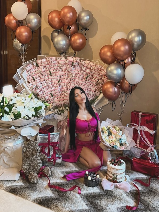 Salah satu yang paling mencolok adalah buket uang raksasa yang tersusun rapi menyerupai kipas besar, dengan dominasi pecahan berwarna merah muda. Buket uang tersebut dipajang tepat di belakang Denada dan menjadi latar utama dalam beberapa potretnya. Foto: Instagram/@denadaindonesia