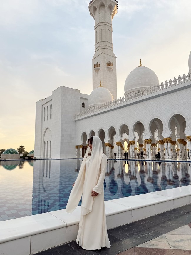 Dalam balutan dress panjang yang menjuntai, Marsha berpose berdiri di tepi kolam yang ikonik di Masjid Agung Sheikh Zayed. Foto: Dok. Instagram @aruanmarsha.