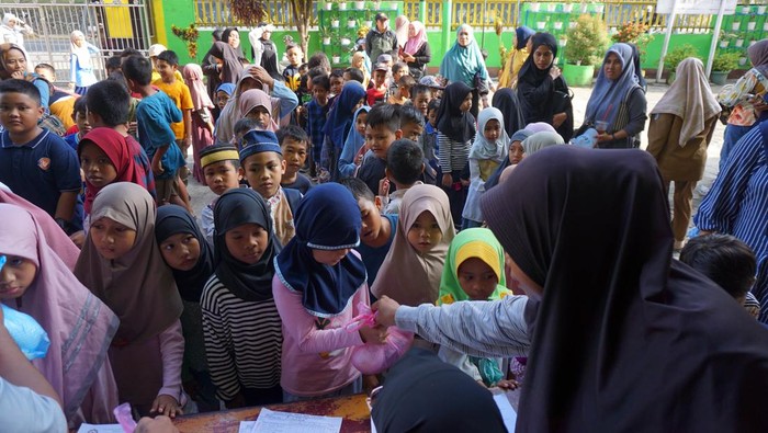 Guru membagikan paket MBG di SD Al Jihad Kota Sorong, Papua Barat Daya, Senin (22/12/2025). Sejumlah sekolah di Papua Barat Daya mulai membagikan paket MBG seminggu sekali berupa buah, roti, susu, kue kering, keripik tempe dan kue basah. ANTARA FOTO/Olha Mulalinda