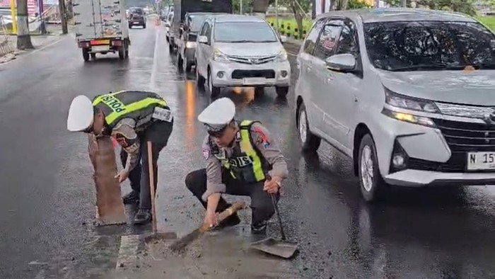 Gercep Personel Satlantas Polres Batu Bersihkan Tumpahan Semen di Jalan
