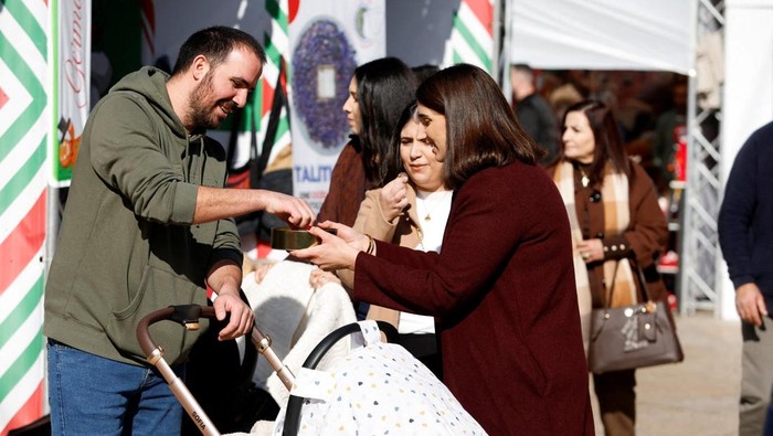 Palestinian Maria Khoury gives samples of her chocolates in a Christmas market, in the Manger Square, near the Church of the Nativity in Bethlehem in the Israeli-occupied West Bank, December 14, 2025. REUTERS/Mussa Qawasma