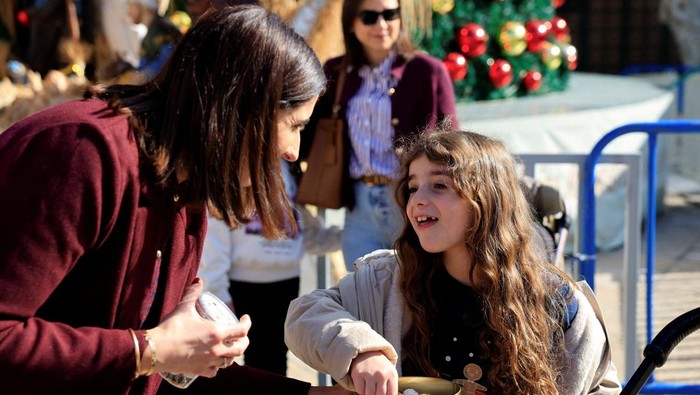 Palestinian Maria Khoury gives samples of her chocolates in a Christmas market, in the Manger Square, near the Church of the Nativity in Bethlehem in the Israeli-occupied West Bank, December 14, 2025. REUTERS/Mussa Qawasma