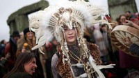 Seorang peserta mengenakan busana druid dan hiasan kepala tradisional saat mengikuti perayaan winter solstice di Stonehenge, Wiltshire, Inggris. REUTERS/Isabel Infantes