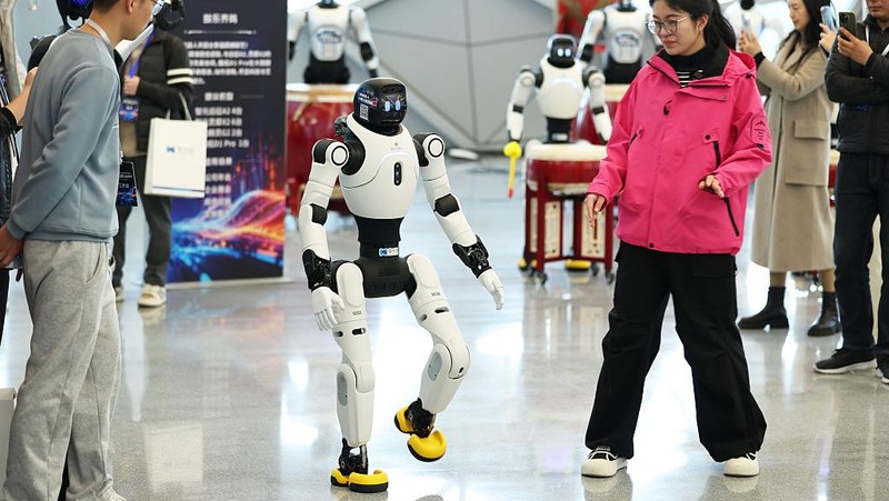 SHANGHAI, CHINA - DECEMBER 22: A humanoid robot interacts with visitors during the launch event of Botshare, or Qingtian Rental, on December 22, 2025 in Shanghai, China. China launches its first open robot rental platform, Qingtian Rental, in Shanghai. Covering 50+ cities, it offers humanoid robots for commercial and industrial use, with expansion to 200+ cities by 2026. (Photo by Tang Yanjun/China News Service/VCG via Getty Images)