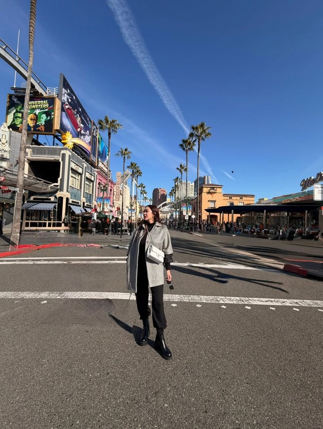 Boots hitam memberi kesan edgy, sementara flap bag Chanel warna putih menambah tampilan klasik dan timeless. Foto: Instagram/@aurakasih