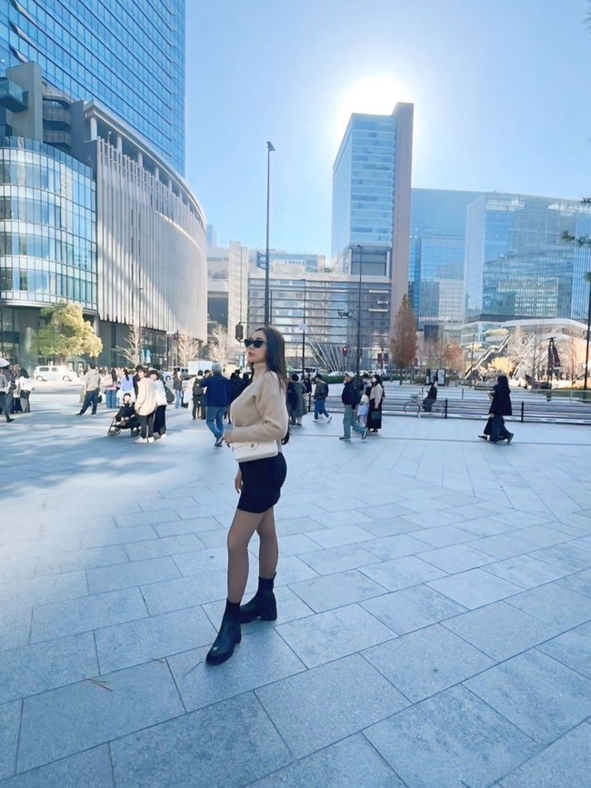 Aura Kasih tampak mengenakan sweater krem dipadu rok pendek dan boots hitam. Kacamata hitam hadir sebagai pelengkap penampilan. Foto: Instagram/@aurakasih