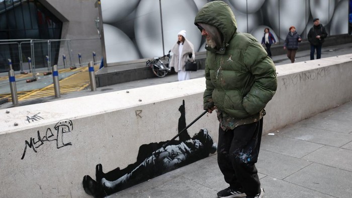 Sebuah mural baru yang diduga merupakan karya seniman anonim Banksy mencuri perhatian publik di Tottenham Court Road, London, Inggris, Selasa (22/12/2025). Mural tersebut langsung menyedot perhatian pejalan kaki dan pengguna jalan yang melintas di kawasan pusat kota London itu. REUTERS/Isabel Infantes